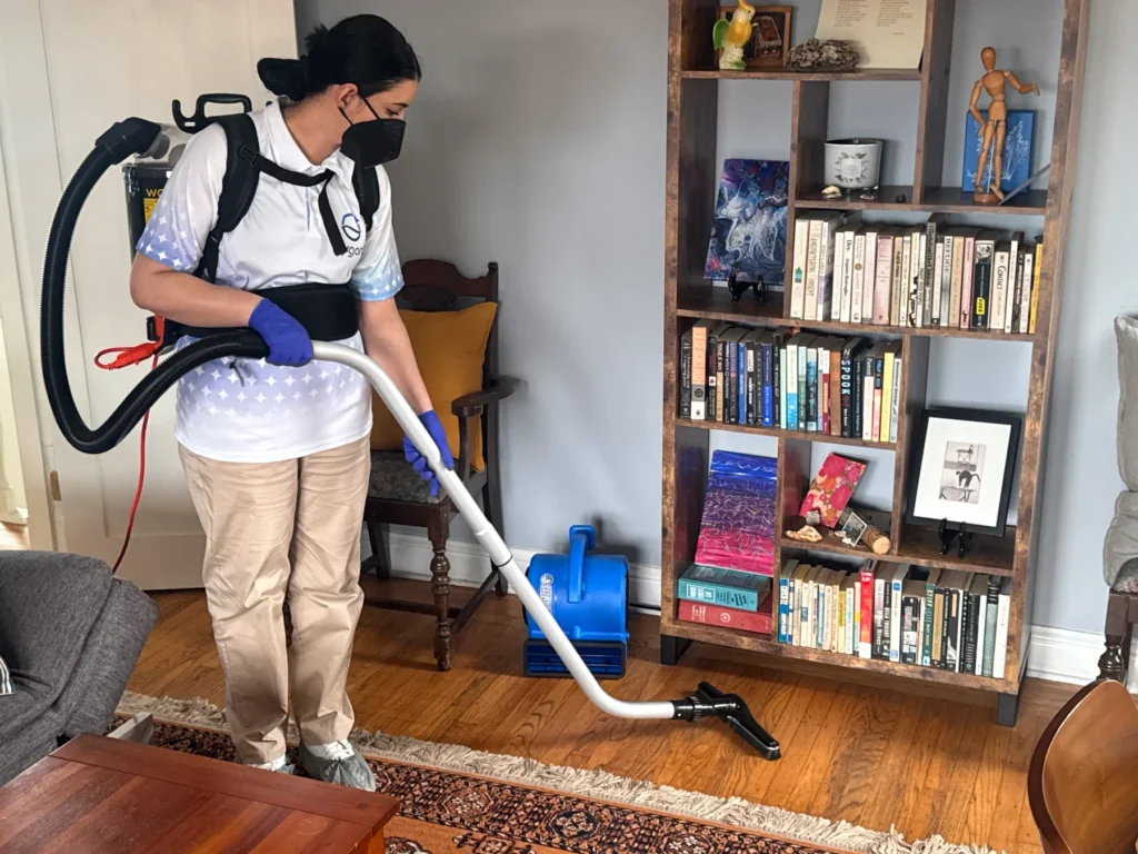 Sygora cleaner vacuuming a hardwood floor with a backpack vacuum.