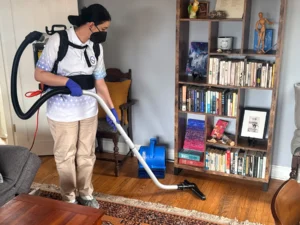 Sygora cleaner vacuuming a hardwood floor with a backpack vacuum.