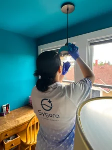 Sygora cleaner wiping a pendant light fixture.