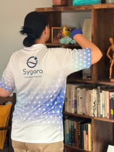 Sygora cleaner dusting a bookshelf.