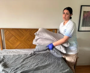 Sygora cleaner making a bed with fresh linens.