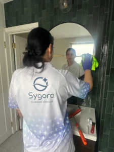 Sygora cleaner polishing a bathroom mirror.