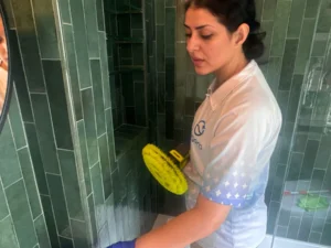 Sygora cleaner scrubbing shower tile with a powered brush.