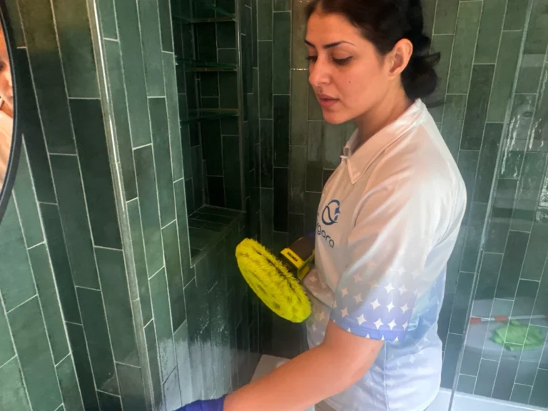Sygora cleaner scrubbing shower tile with a powered brush.