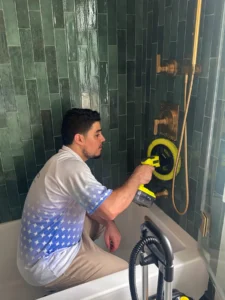 Sygora cleaner scrubbing a tiled shower wall.