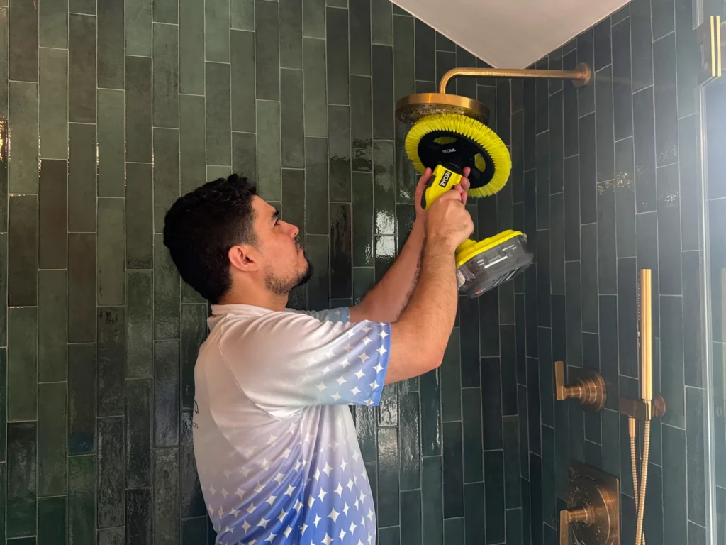 Sygora cleaner scrubbing tile around a shower head.