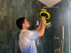 Sygora cleaner scrubbing tile around a shower head.