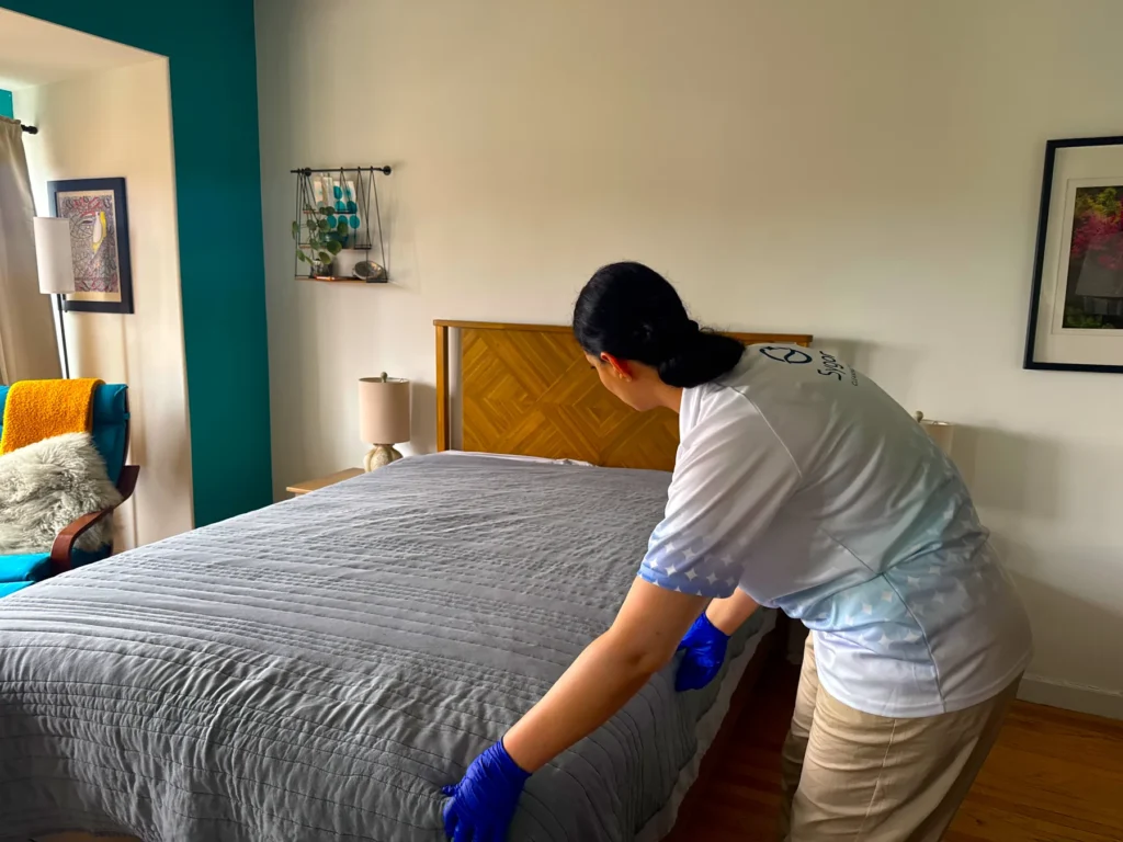 Sygora cleaner smoothing a bedspread.