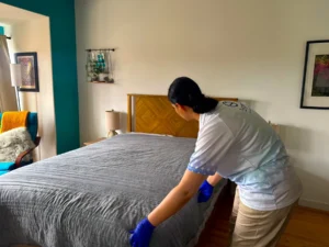 Sygora cleaner smoothing a bedspread.