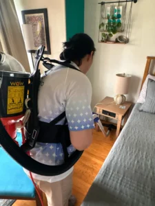 Sygora cleaner vacuuming a bedroom with a backpack vacuum.