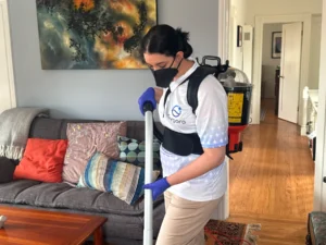 Sygora cleaner vacuuming beside a sofa.