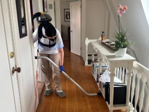 Sygora cleaner vacuuming a hallway floor.