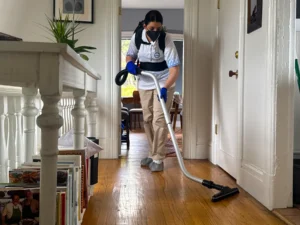 Sygora cleaner vacuuming a landing beside a stair railing.
