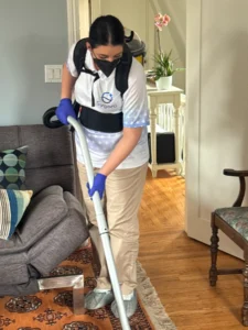 Sygora cleaner vacuuming a living room rug.