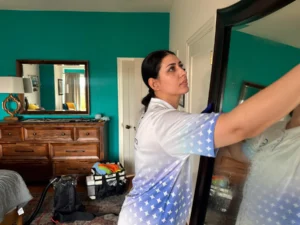 Sygora cleaner wiping a tall bedroom mirror.