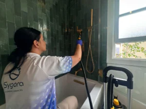 Sygora cleaner wiping shower fixtures and tile.
